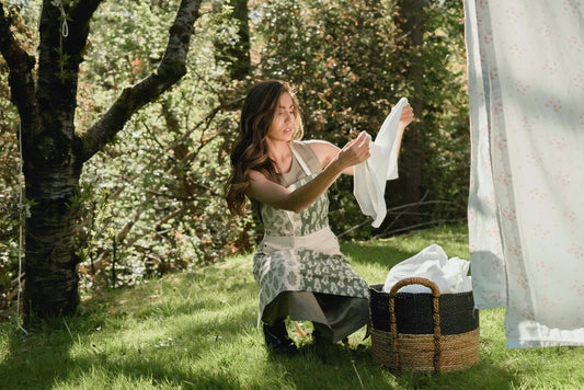 Eine Frau, welche nachhaltig mit EccoClean Waschmittel gewaschen hat und nun Wäsche aufhängt.